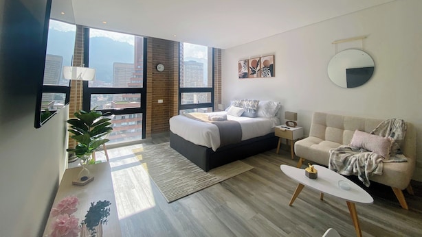 Une chambre moderne avec un grand lit, un canapé, une table basse et une vue sur la ville.