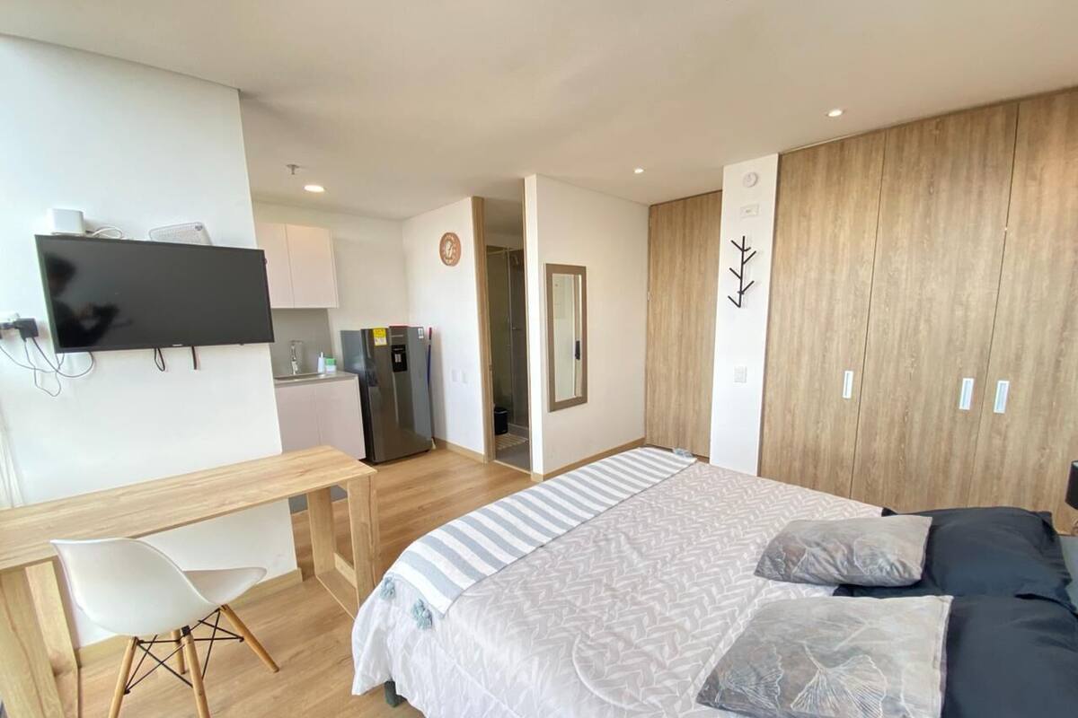 A modern bedroom with a large bed, a desk, and a TV.