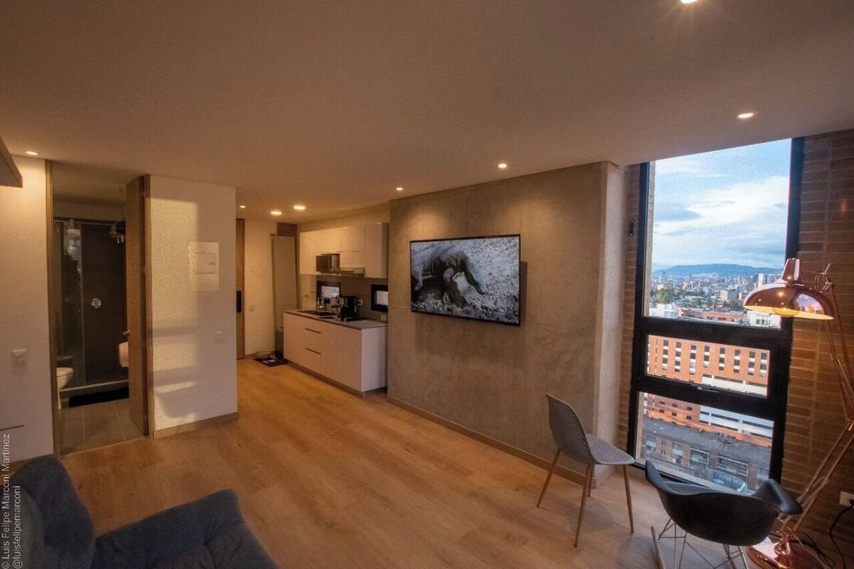 A modern apartment with a kitchen, dining area, and a large window with a city view.