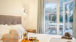 A bedroom with a bed, bedside table, and a tray with croissants and honey.