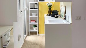 Eine kleine Küche mit weißem Arbeitsplatz, einem Spülbecken und einem kleinen Fenster.