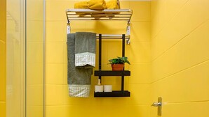 Ein Badezimmer mit gelben Wänden, einer Duschkabine aus Glas, einem weißen Waschbecken und einer Toilette.