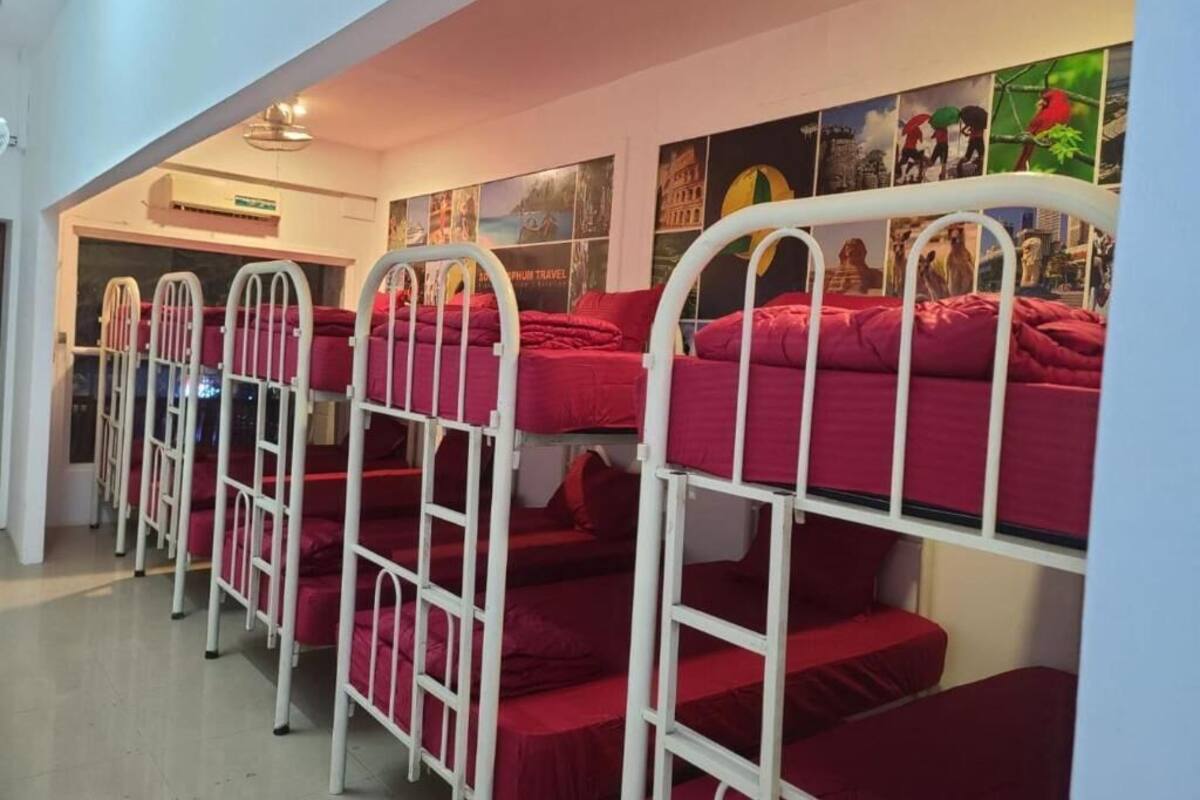 A dormitory room with bunk beds, a ceiling fan, and a wall with travel posters.