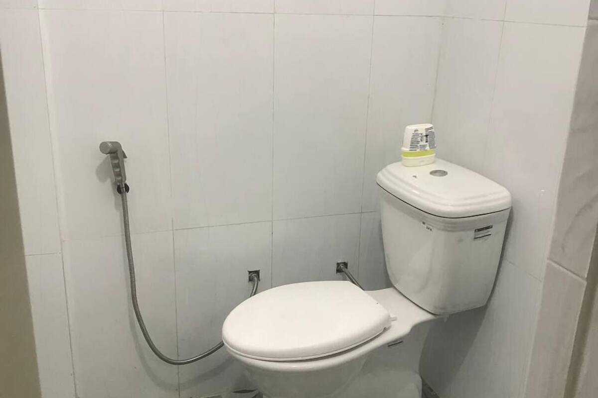 A small bathroom with a toilet, a shower, and a toilet paper holder.