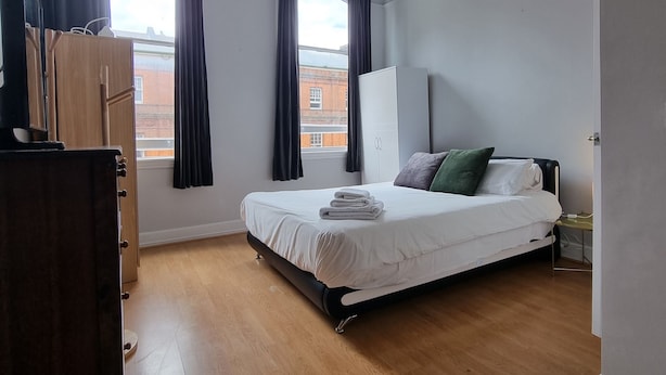 Une chambre à coucher avec un lit, une armoire, un bureau et une fenêtre avec des rideaux.