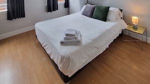 Une chambre d’hôtel avec un grand lit, une table de chevet avec une lampe et une armoire.