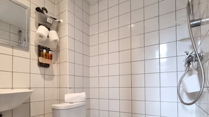 Une salle de bain équipée de toilettes, d’un lavabo, d’une douche et d’un miroir.