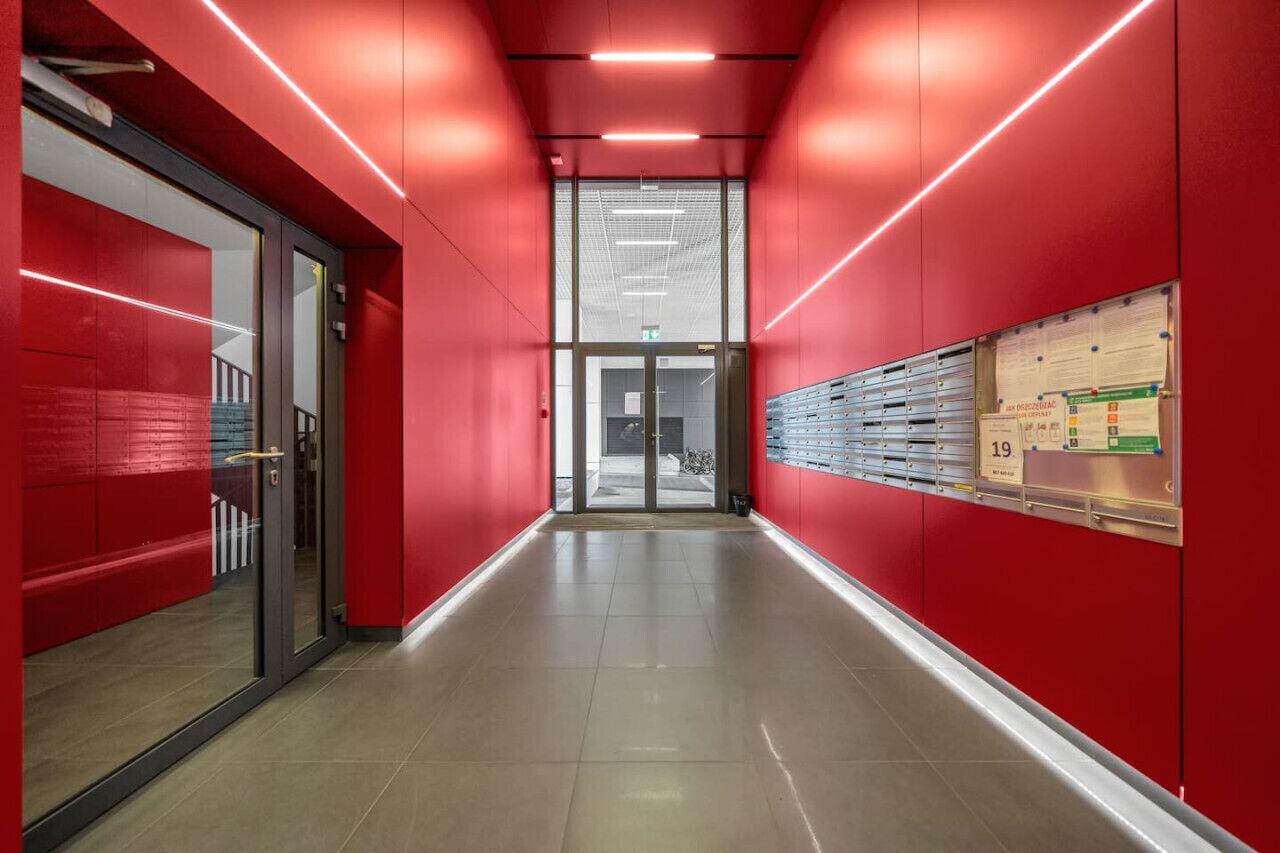 A corridor with red walls, glass doors, and a row of lockers on the right.
