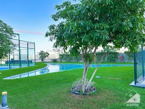 Relax by the serene pool surrounded by a well-maintained lawn and a small tree.