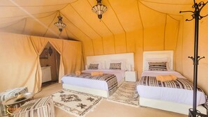 Una camera da tenda con due letti, un tavolino e una lampada.