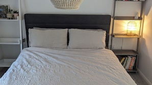 A neatly made bed with a white quilt, two pillows, and a bedside lamp on a shelf. - Tranquil Wells Retreat (Wells)