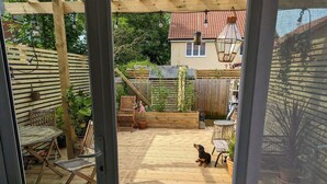 A wooden deck with outdoor furniture, a dog, and a house in the background. - Tranquil Wells Retreat (Wells)