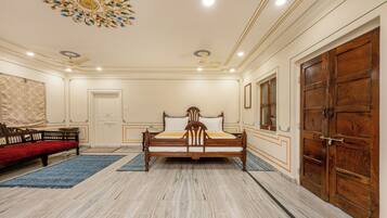 A bedroom with a large bed, wooden wardrobe, and a red sofa.