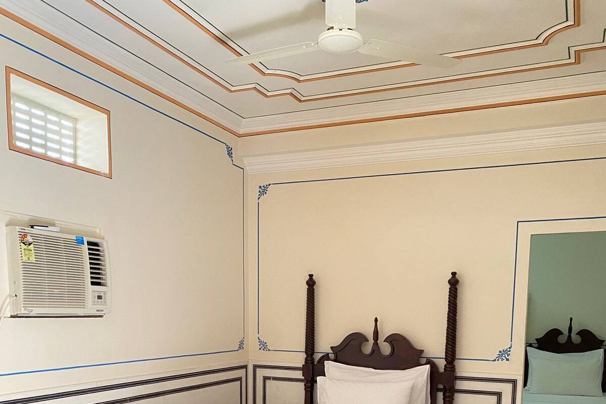Un lit bien fait, avec une tête de lit en bois, une petite table de chevet et un climatiseur fixé au mur.