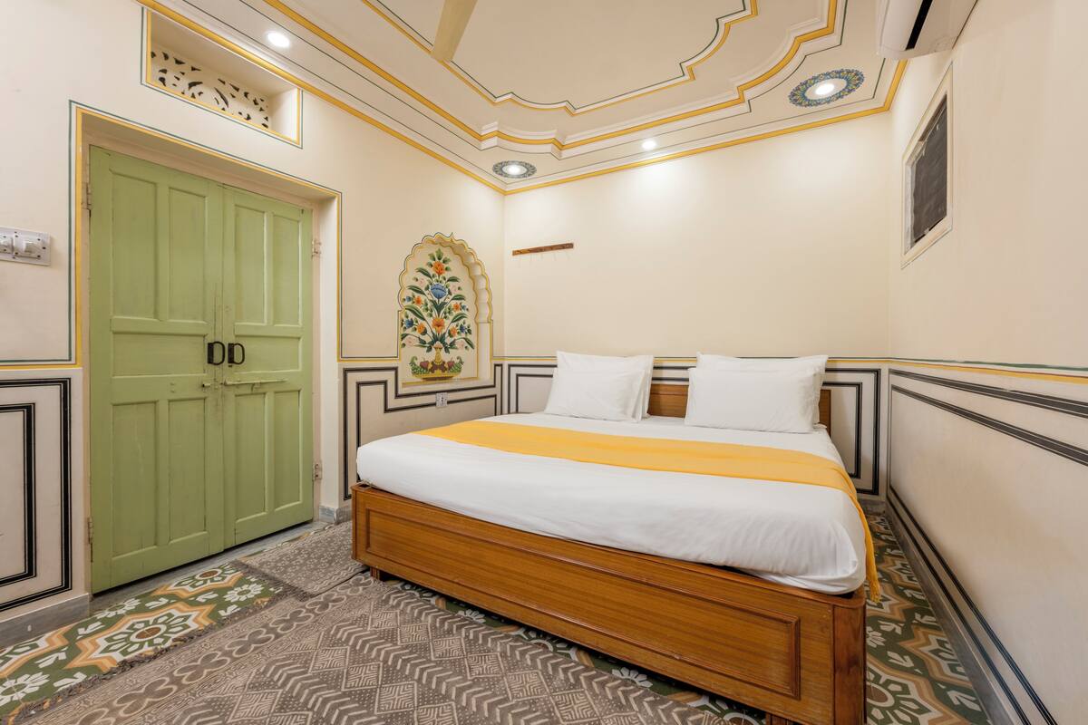 Une chambre avec un lit en bois, une porte verte, un sol à motifs et un plafond décoratif.