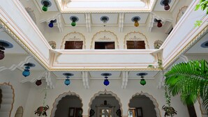 Ein mehrgeschossiges Atrium mit aufwendig gestalteten weißen Wänden, mehreren Balkonen und hängenden Dekorationen.