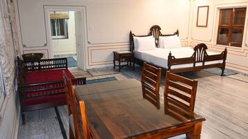 A room with a wooden bed, a wooden table with chairs, a red sofa, and a small table with a bowl.