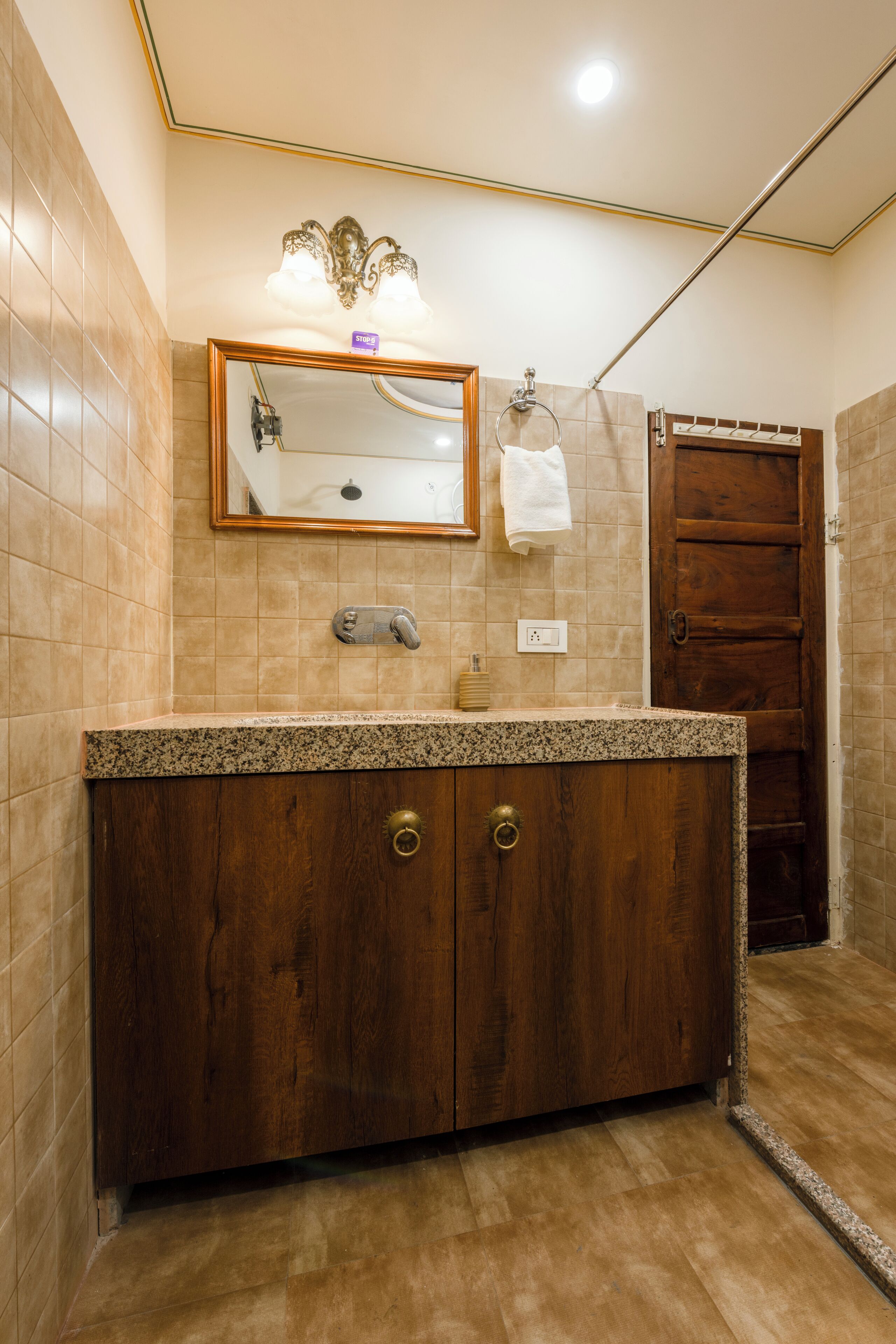 A bathroom with a wooden vanity, a mirror, and a towel hanging on the wall.