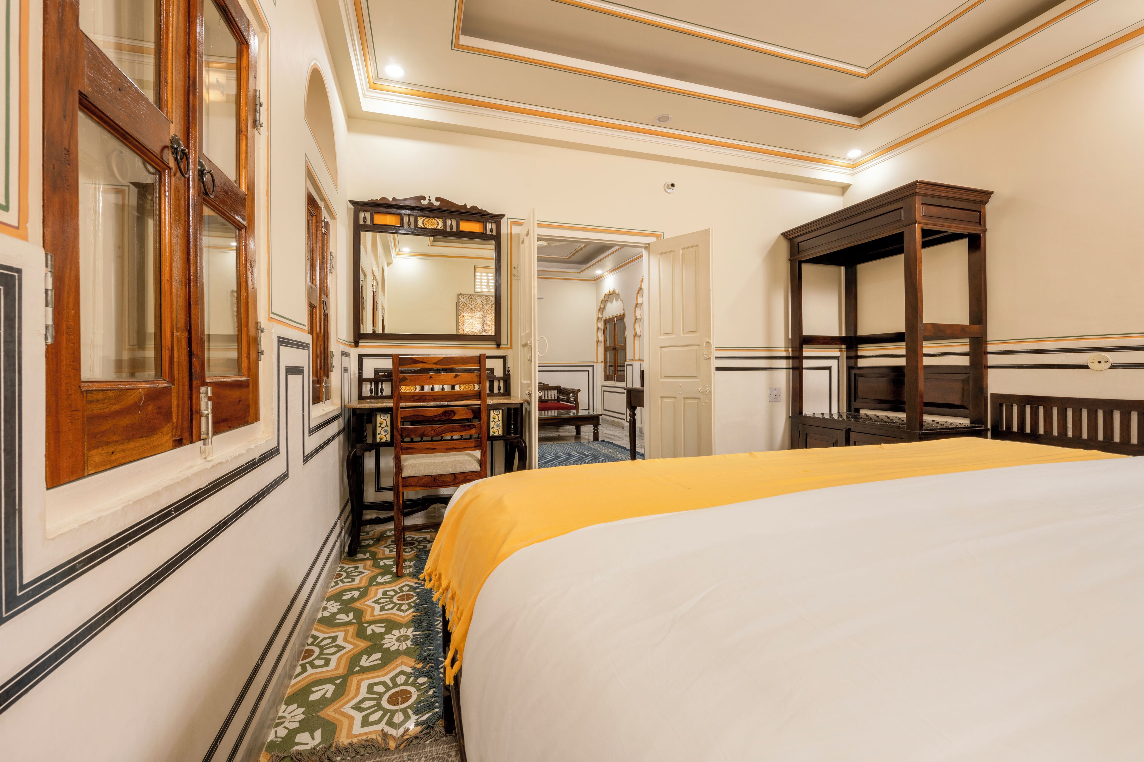 A hotel room with a large bed, a wooden dresser, a mirror, and a small table.
