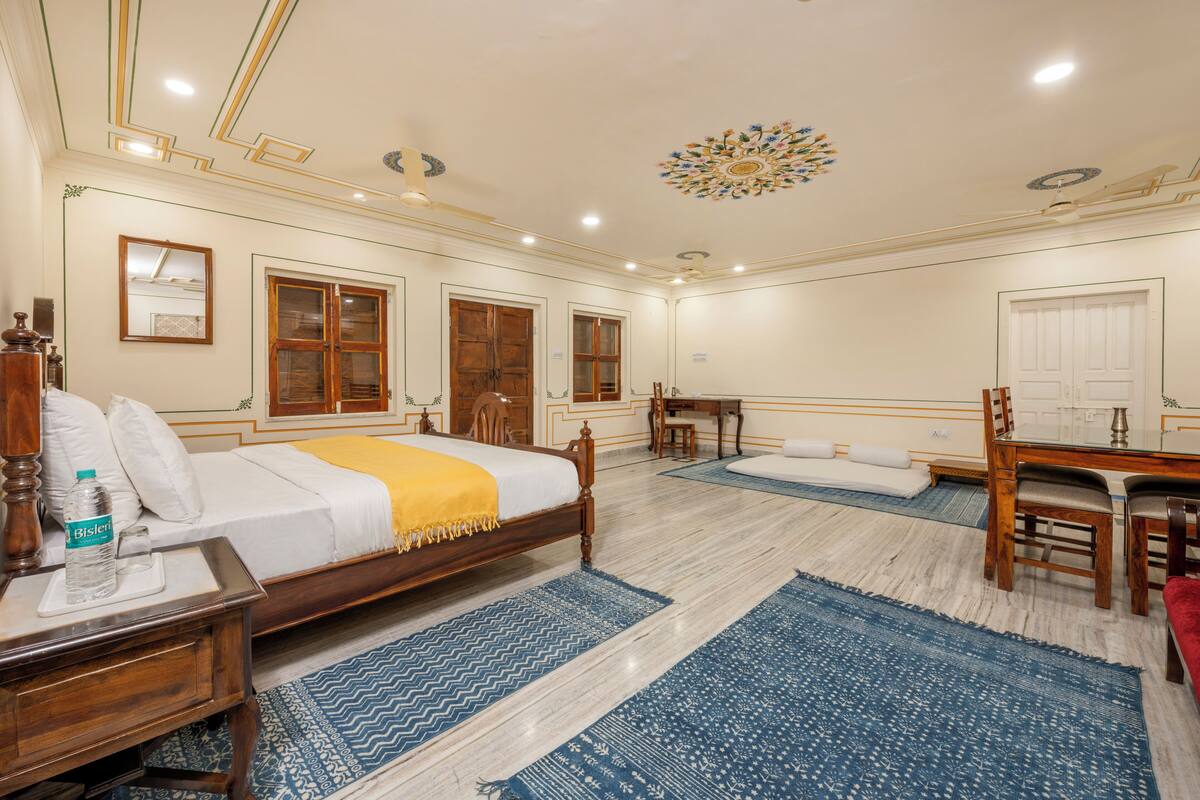 Une chambre d’hôtel spacieuse, dotée d’un grand lit, de meubles en bois et d’un plafond décoratif.