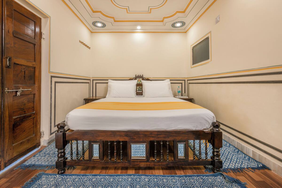 Une chambre avec un lit en bois, une armoire en bois et un tapis à motifs.
