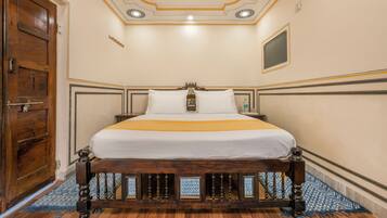 A room with a wooden bed, a wooden wardrobe, and a patterned rug.