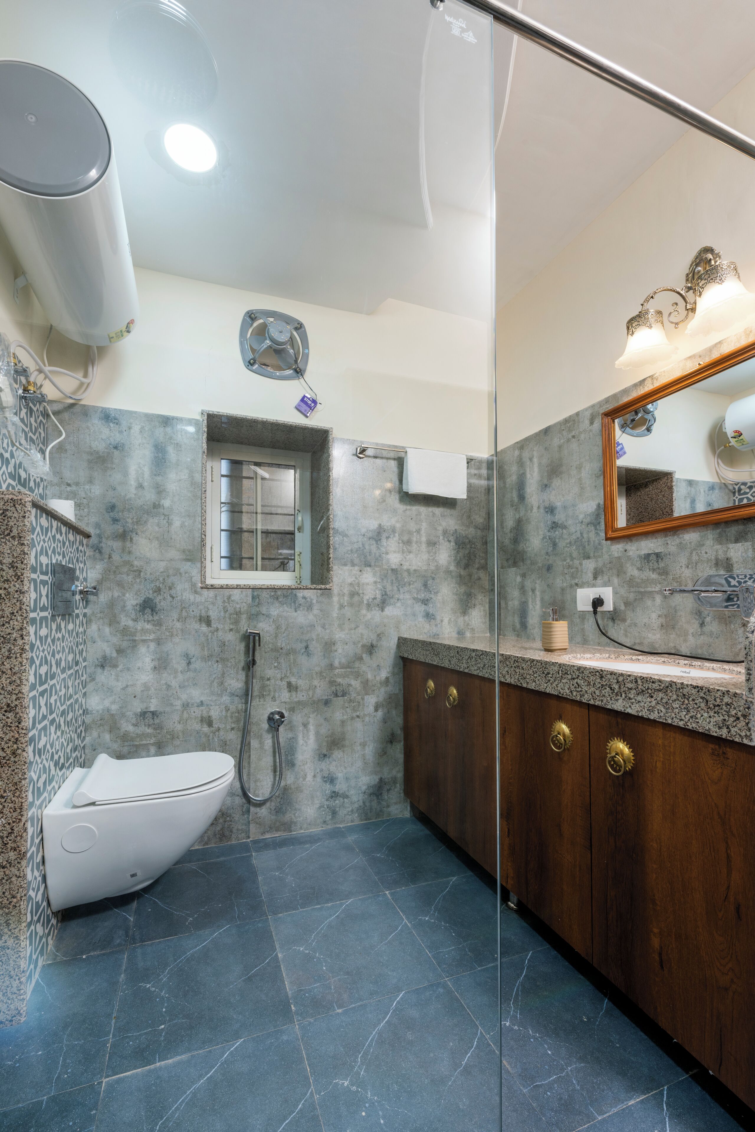 A modern bathroom with a white toilet, a shower, a vanity with a mirror, and a small window.