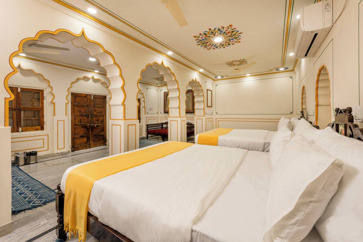 Une chambre d’hôtel avec deux lits, des arches décoratives et un plafond orné.