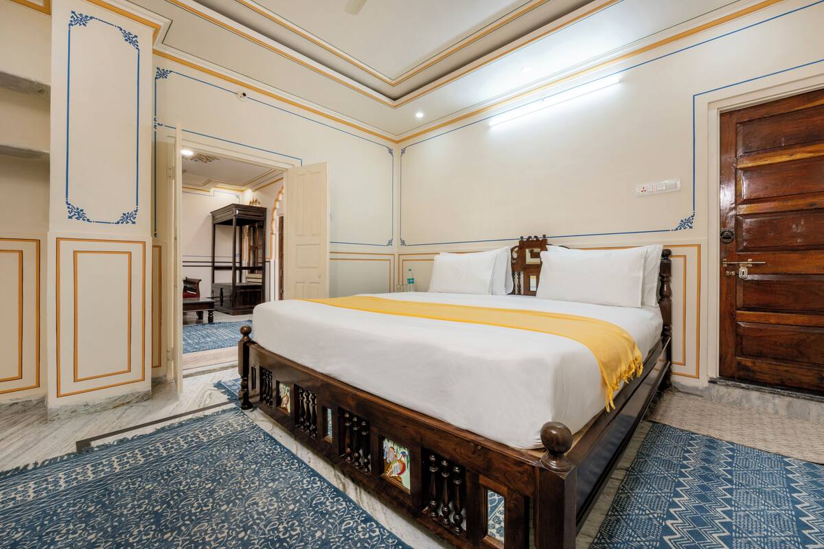 Une chambre spacieuse avec un grand lit, une tête de lit en bois et un tapis à motifs bleus.