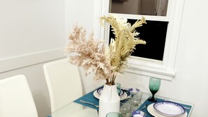 A dining table set with blue and white plates, green glassware, and a vase with dried flowers. - Pretty home in the heart of Edmonton. Main floor, Pet-Friendly! (Edmonton)