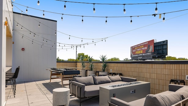 An outdoor patio with a sofa set, a barbecue grill, and string lights.