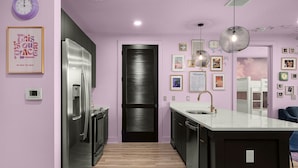 A modern kitchen with a stainless steel refrigerator, a black door, and a white countertop.