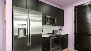 A compact kitchen with a stainless steel refrigerator, a microwave, and an oven.