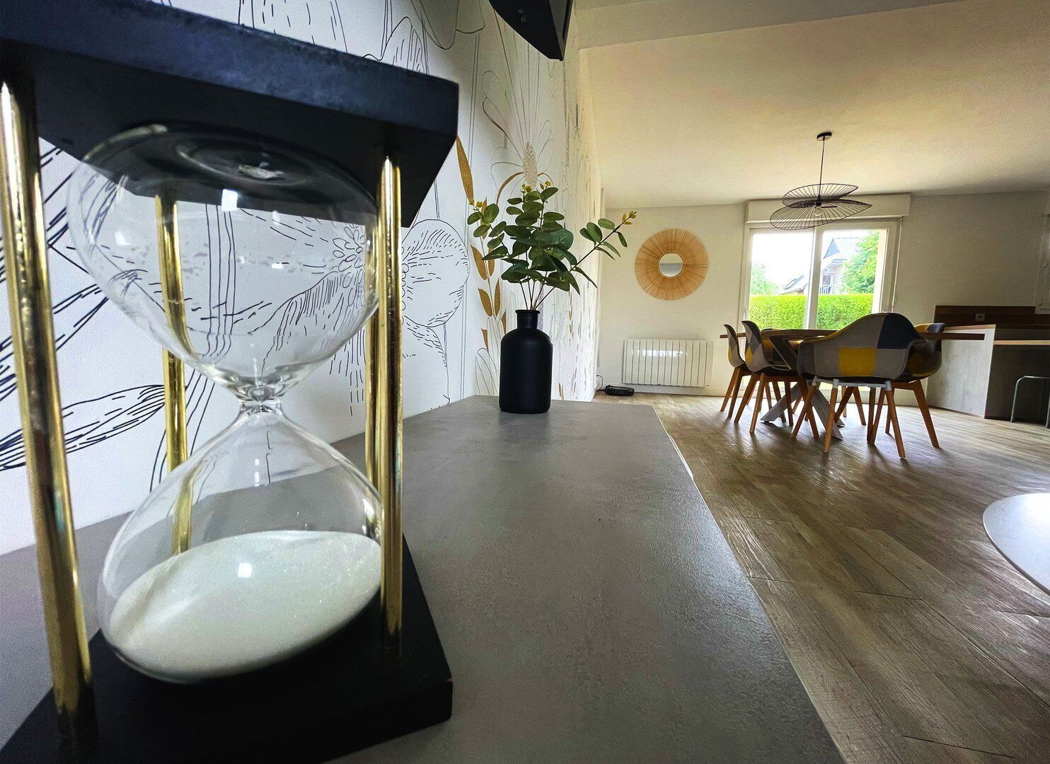 Un comedor moderno con una mesa, sillas y una lámpara de arena como adorno central.