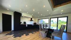 A modern kitchen with a black countertop, a built-in stove, and a large window overlooking a garden. - house Porzh Loaz. (Plouha)