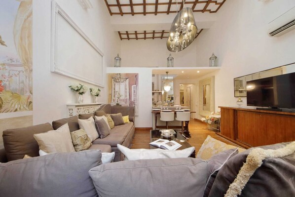 A living room with a sofa set, a television, and a chandelier. - Imperial - Luxury Grand Opening (Roma)