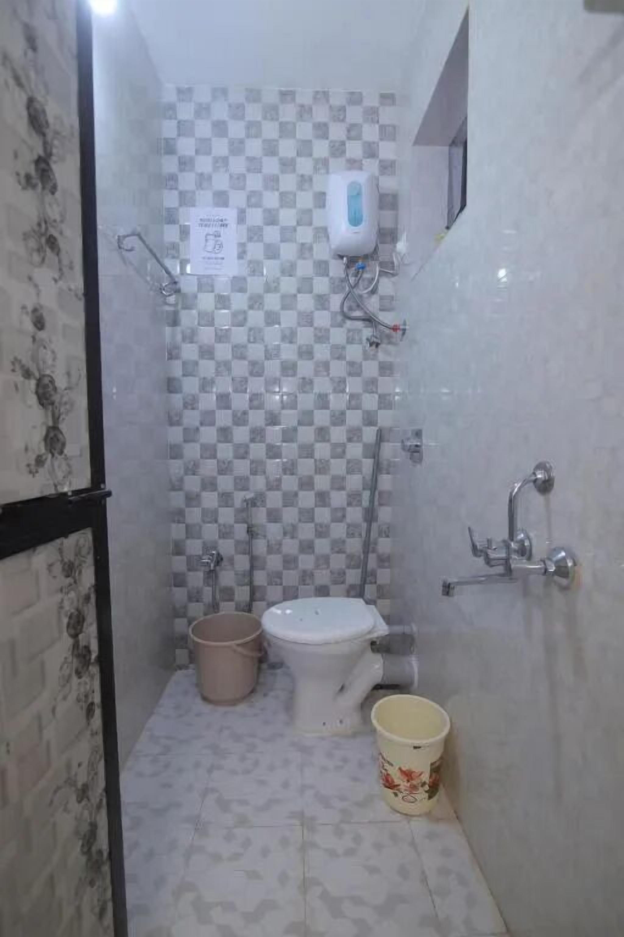 A small bathroom with a toilet, a sink, a hand dryer, and a bucket.