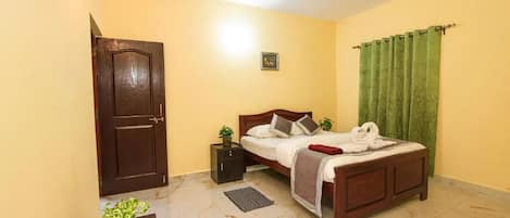 A bedroom with a bed, a nightstand, a ceiling fan, a door, and a green curtain.