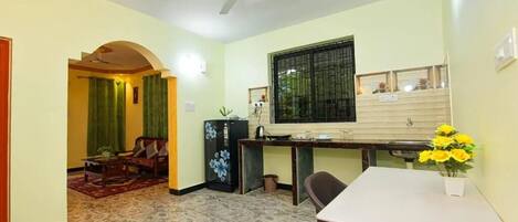 Un espacio habitable compacto con comedor, kitchenette y zona de estar con sofá y mesa de centro.