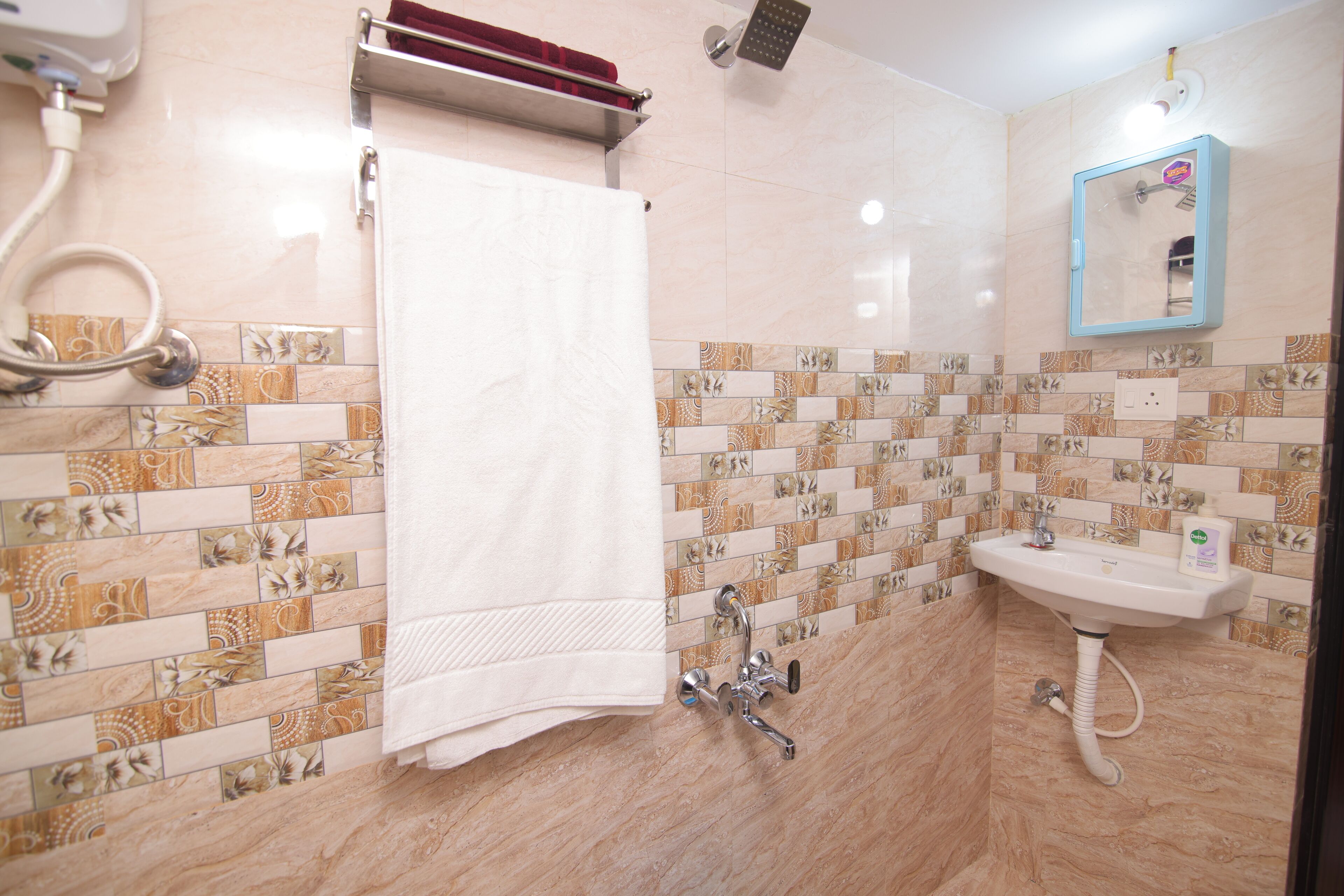 A bathroom with a tiled floor, a white sink, a mirror, and a towel rack.