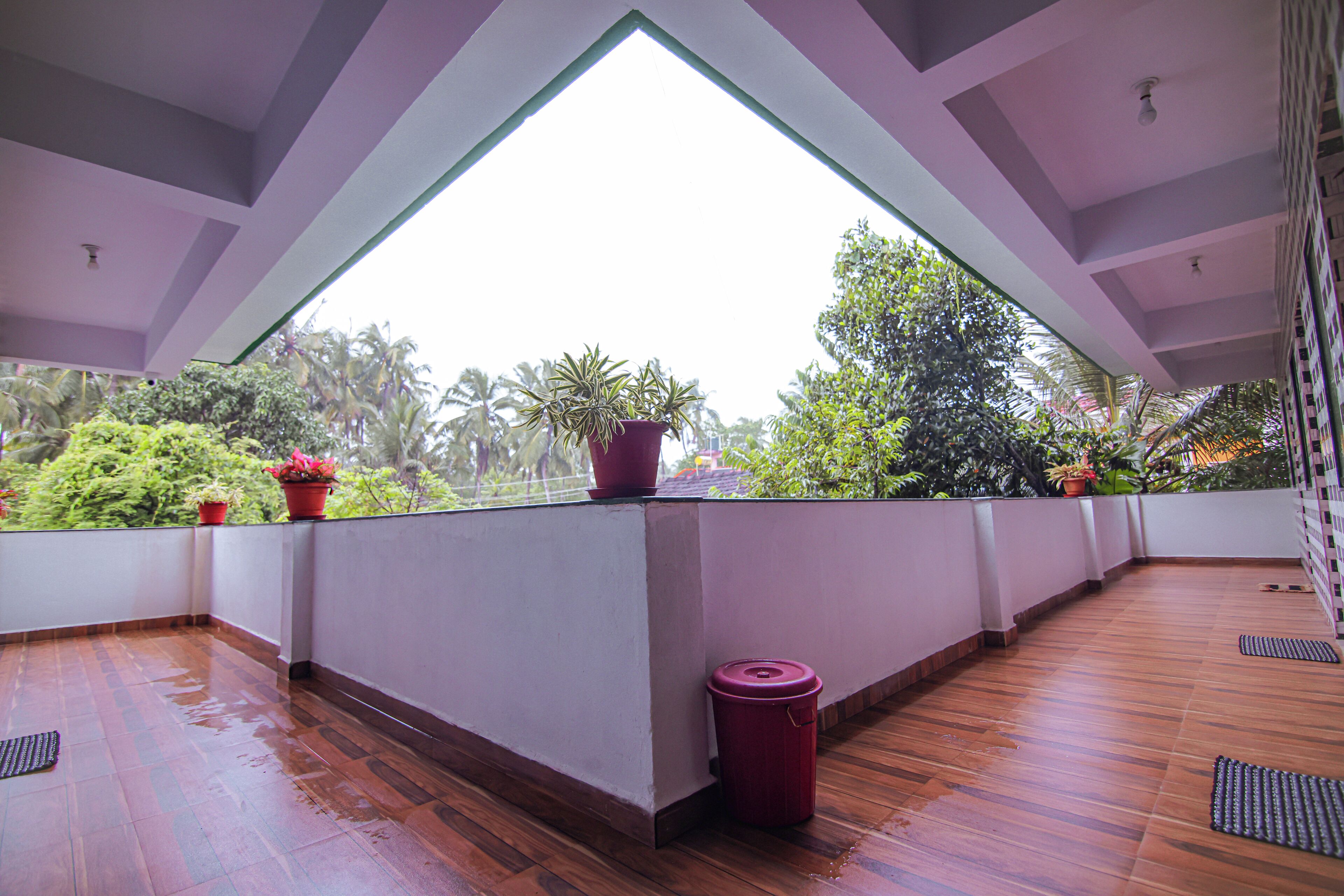 Un balcon spacieux doté d’un plancher en bois, de plantes en pot et offrant une vue sur une végétation luxuriante.