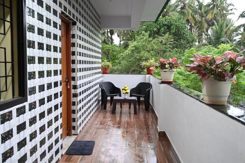 A balcony with a checkered floor, two chairs, a table with yellow flowers, and potted plants.