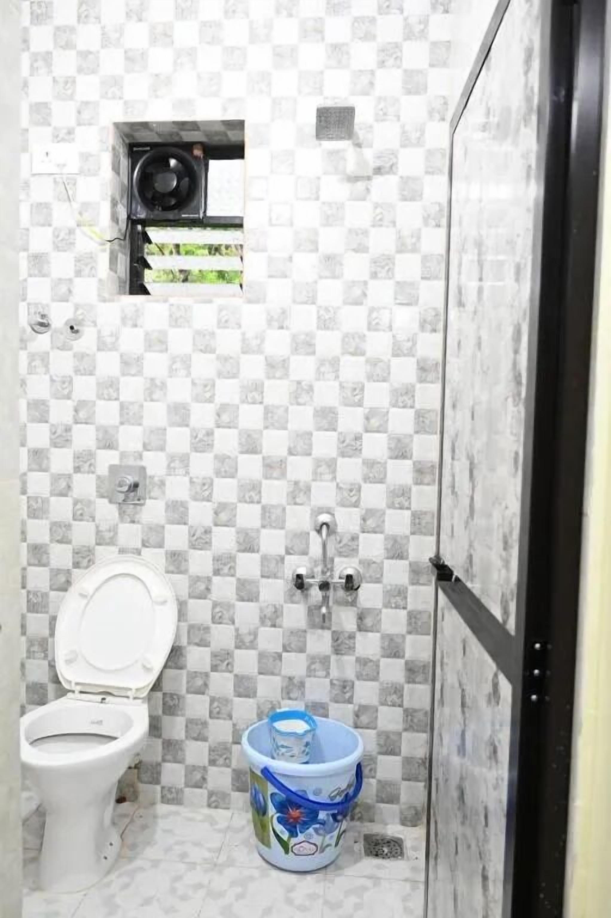 A small bathroom with a toilet, a shower, and a bucket.