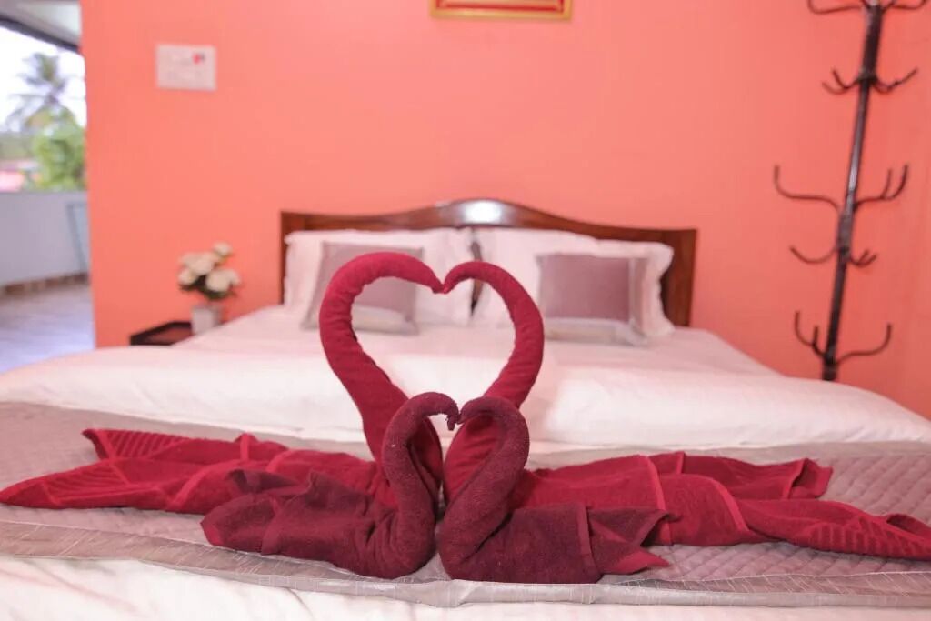 A bed with a heart-shaped towel arrangement and a wooden headboard.