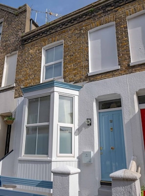 A two-story building with a bay window and a blue door. - Cute Cosy Cottage | Ramsgate Historic Area | 2bd (Kent)