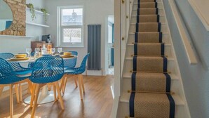 A modern dining area with a staircase leading to an upper level. - Cute Cosy Cottage | Ramsgate Historic Area | 2bd (Kent)