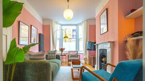 A cozy living room with a sofa, armchairs, a fireplace, and a large window. - Cute Cosy Cottage | Ramsgate Historic Area | 2bd (Kent)