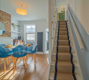 A modern dining area with a staircase leading to an upper level. - Cute Cosy Cottage | Ramsgate Historic Area | 2bd (Kent)