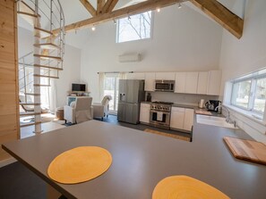 A modern kitchen with a central island, built-in appliances, and a large window.