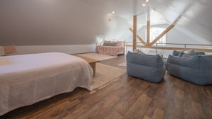 Un dormitorio con una cama, un banco y dos pufs.
